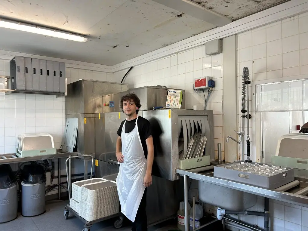 Photo d'un professionnelle en insertion devant son poste de travail(la vaisselle)