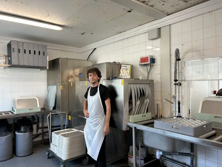 Photo d'un professionnelle en insertion devant son poste de travail(la vaisselle)